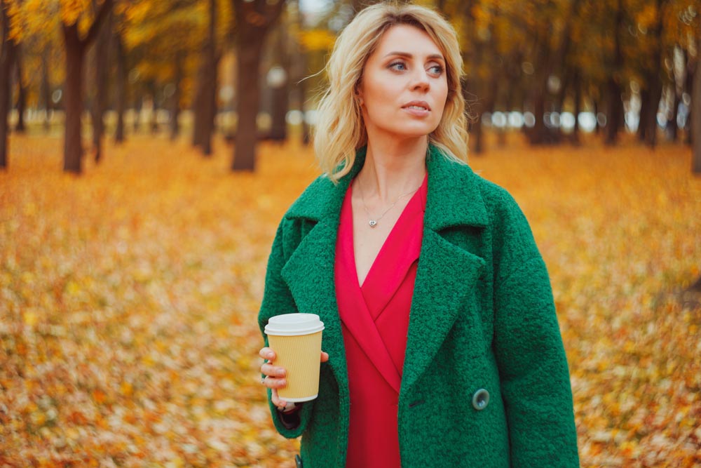 Middle aged woman in autumn park outdoor with take away paper cup